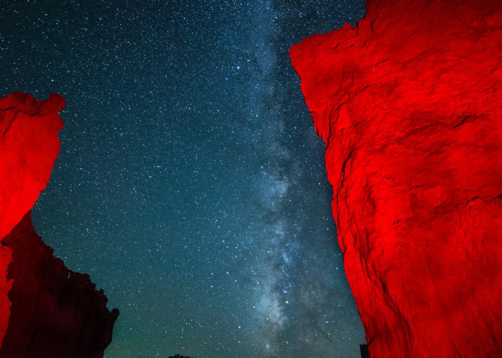 A vibrant view of the Milky Way surrounded by bright red rocks at Bryce Canyon National Park.