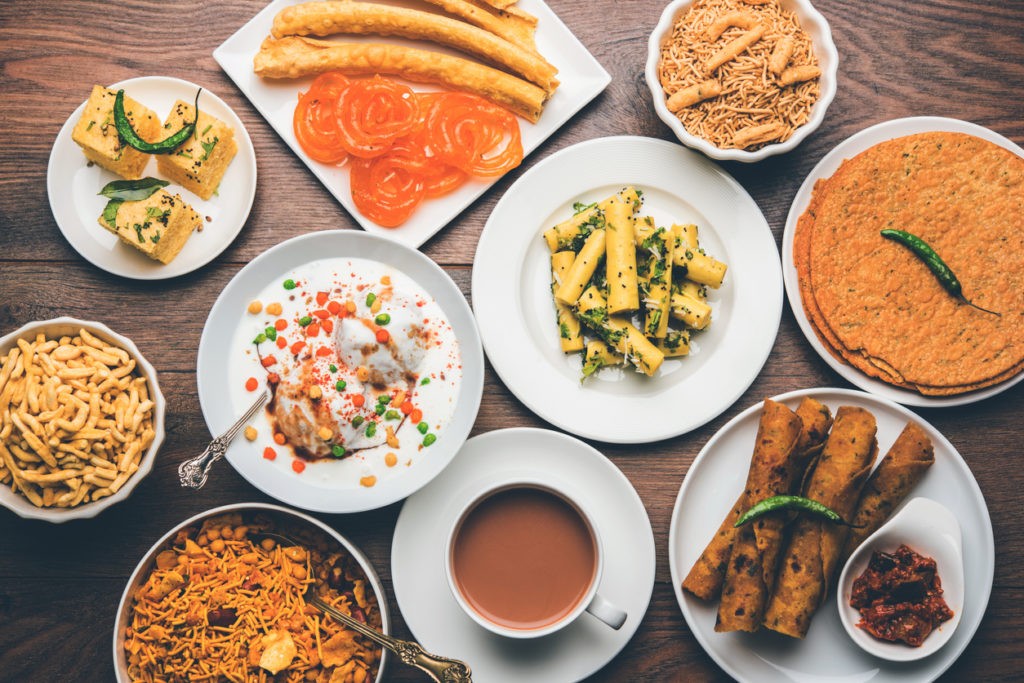 Group of Gujarati snacks like jalebi-fafda, thepla, khaman dhokla, aloo bhujiya, khandvi,khakra, dahi vada, gathiya with hot tea